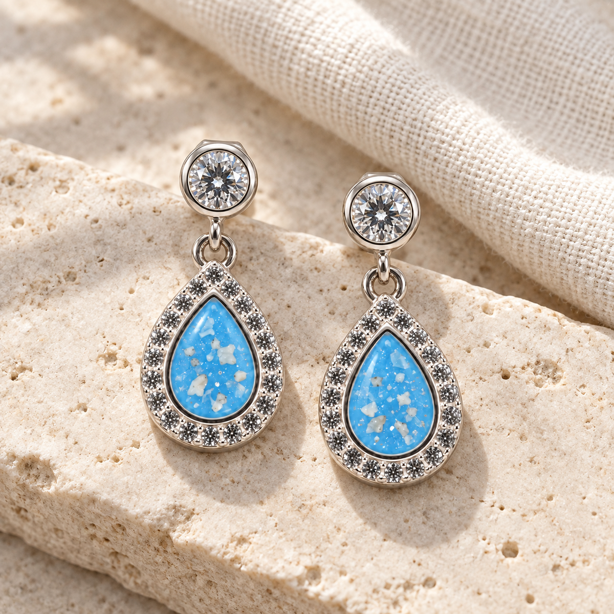 Illustrative lifestyle view of Crystal Halo Teardrop Ashes Earrings — Sky Blue, visible ashes