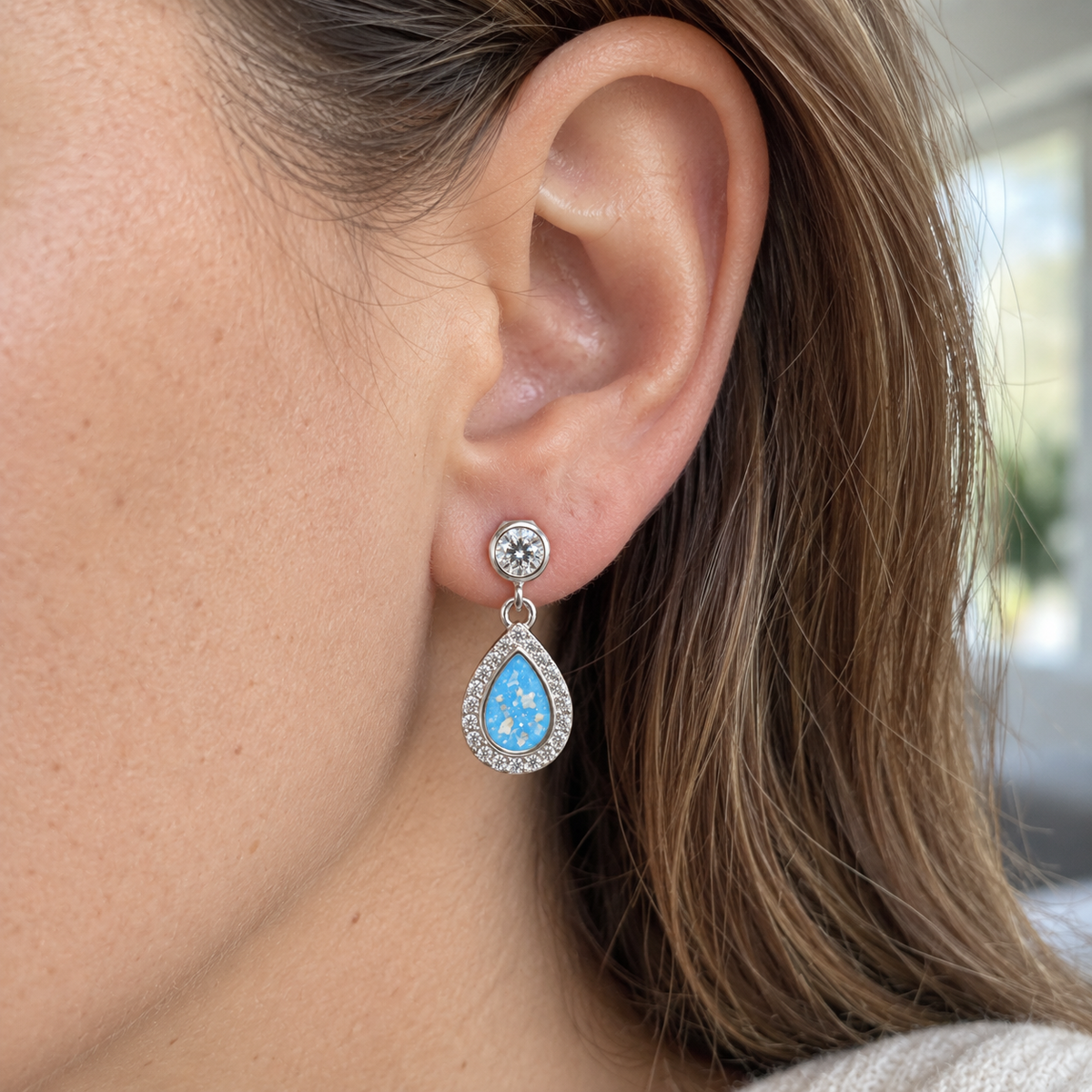 Illustrative worn view of Crystal Halo Teardrop Ashes Earrings — Sky Blue, visible ashes