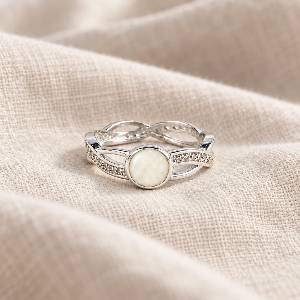 Entwined Breast Milk Ring on pale linen — illustrative milk jewellery preview