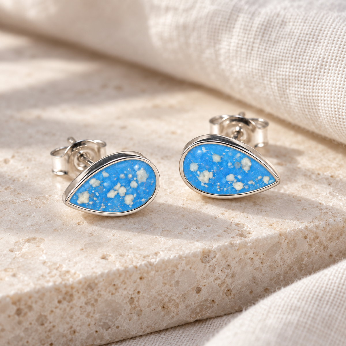 Illustrative lifestyle view of Pear Stud Ashes Earrings — Sky Blue, visible ashes