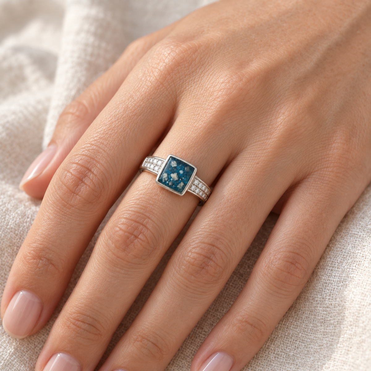 Illustrative worn view of Square Crystal Ashes Ring in Sky Blue, visible ashes