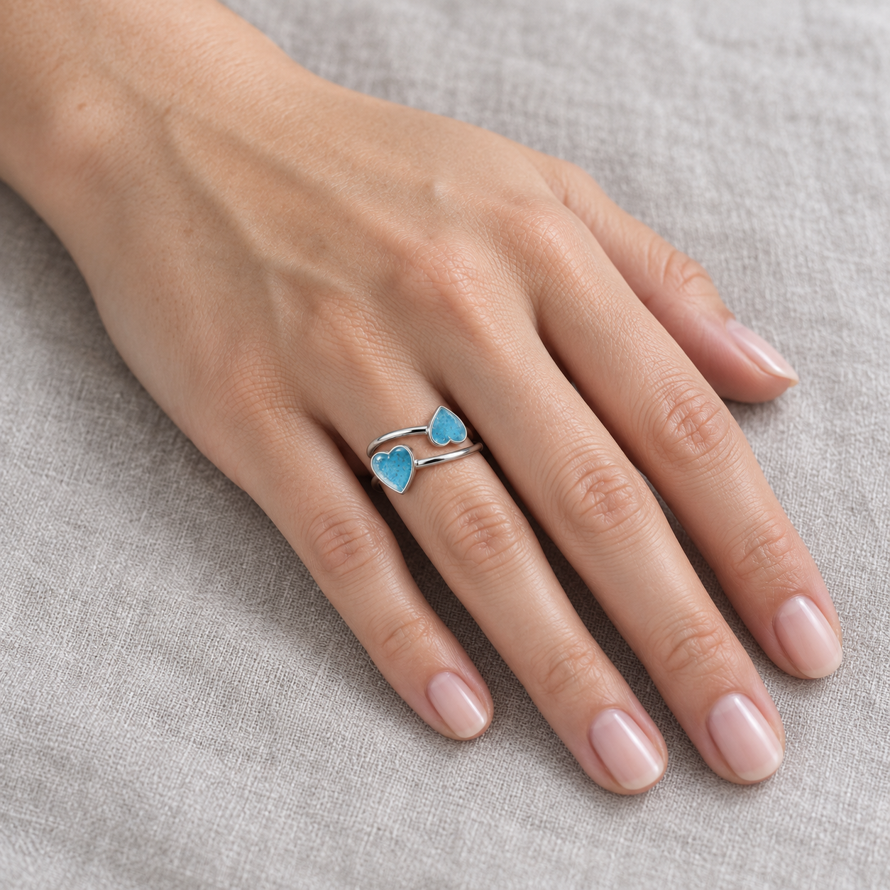 Double Heart Ashes Ring worn around the ring finger in Sky Blue