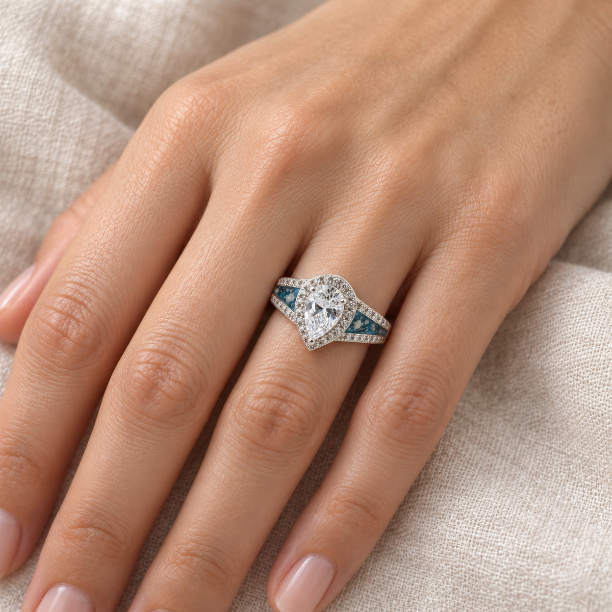 Illustrative worn view of Pear CZ Ashes Ring in Sky Blue