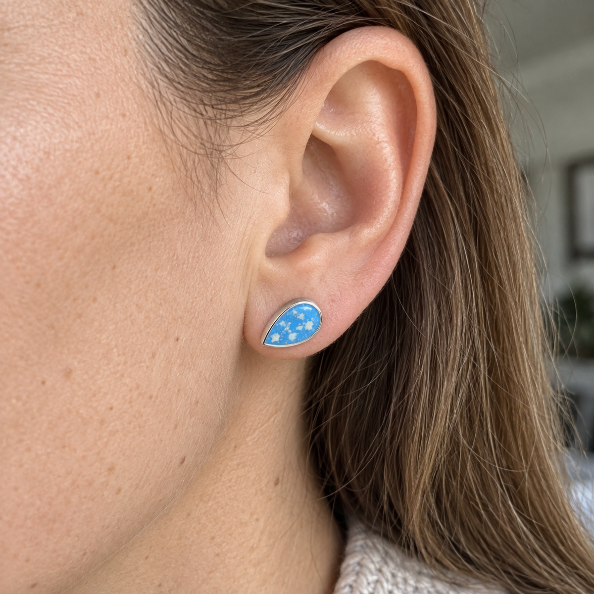 Illustrative worn view of Pear Stud Ashes Earrings — Sky Blue, visible ashes