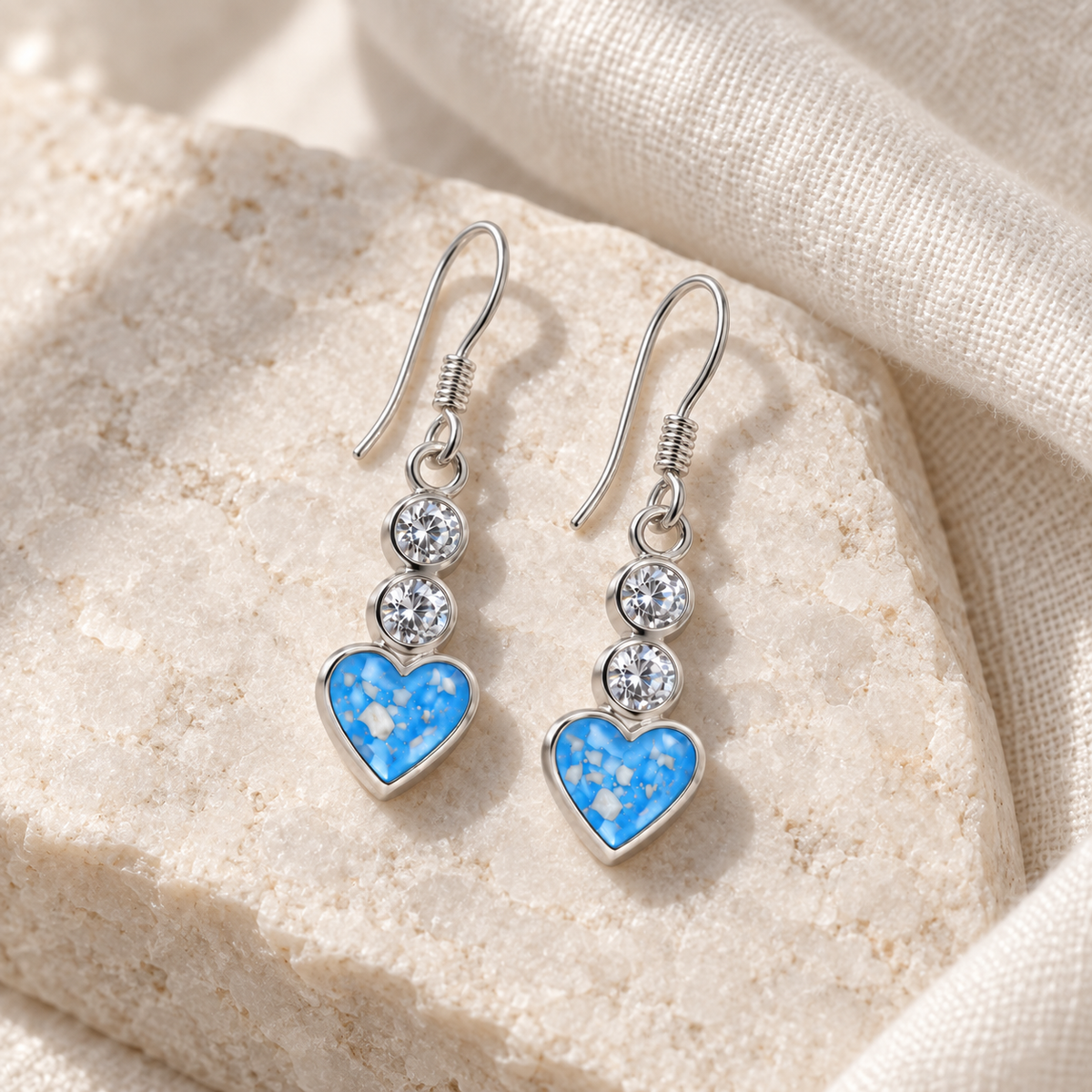 Illustrative lifestyle view of Twin Crystal Heart Drop Ashes Earrings — Sky Blue, visible ashes